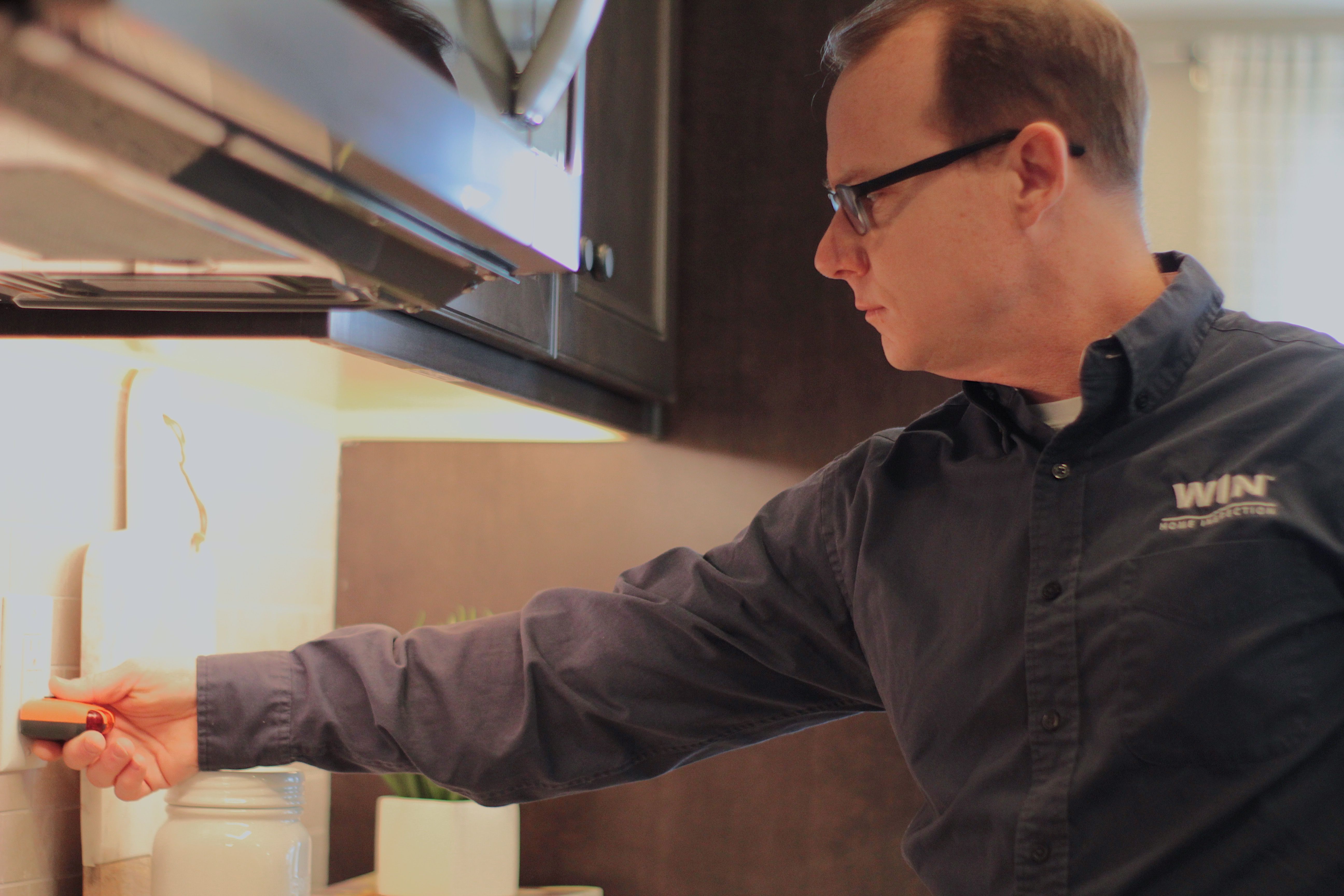 WIN Home Inspector in glasses inspecting microwave.