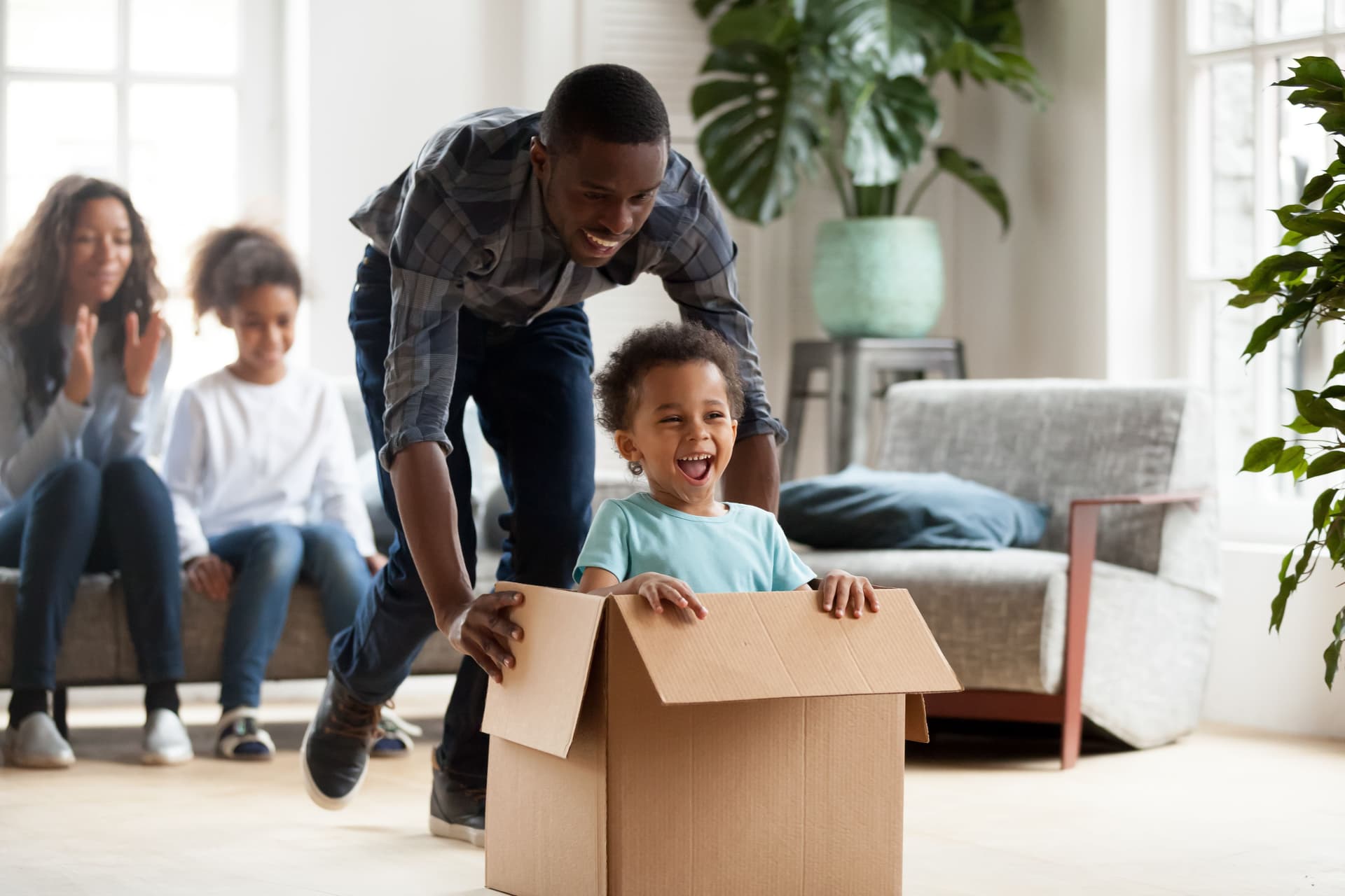 A man pushing his child in a box at their new home